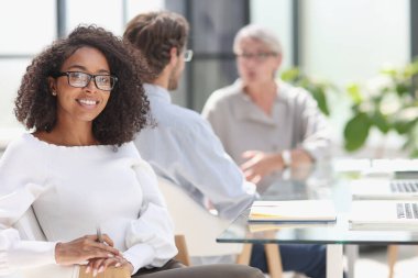 young attractive african american woman in the office sitting at the table