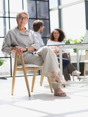 mature woman sitting with laptop looking at camera.