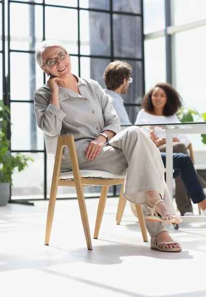 mature woman sitting with laptop looking at camera.