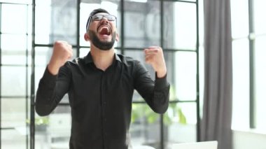 Genç işadamı ofisinde başarısını kutluyor.