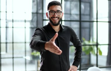 Genç işadamı iş ortağıyla el sıkışıyor. Ofiste, hoş geldiniz.