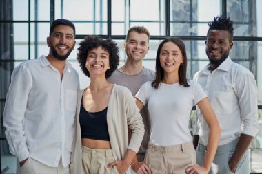 Başarılı yaratıcı iş ekibinin portresi kameraya bakıyor ve gülümsüyor. Başlangıçta çeşitli iş adamları bir arada duruyorlar.