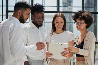 Çevrimiçi projeyi tartışan mutlu genç bayan çalışan, gözlüklü yetenekli takım liderine bilgisayar sunumu yapıyor. Uygulamaları kullanarak laptopta çift olarak çalışan dost canlısı meslektaşlar.