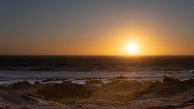 Kayalıklarla okyanusta gün batımı