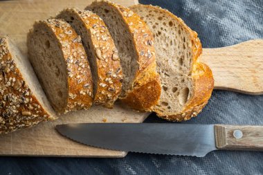 Gri zemin üzerinde dilimlenmiş ekmek parçaları.