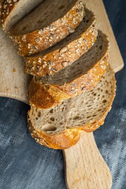 Gri zemin üzerinde dilimlenmiş ekmek parçaları.