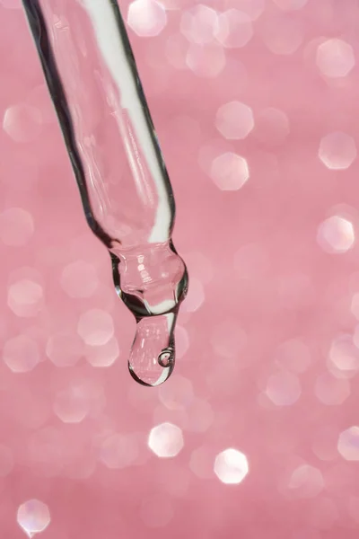 Kozmetikai pipetta egy csepp rózsaszín háttér. — Stock Fotó