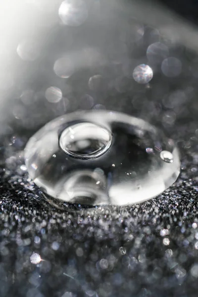 A drop of cosmetic gel on a black shining background. — Stock Photo, Image