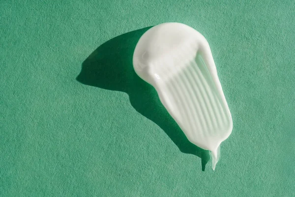 A textura do creme branco sobre um fundo verde. — Fotografia de Stock