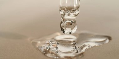 Bej arka planda pipeti olan serumun veya yağın dokusu.