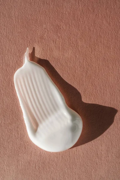 Pembe arka planda beyaz kremin dokusu.