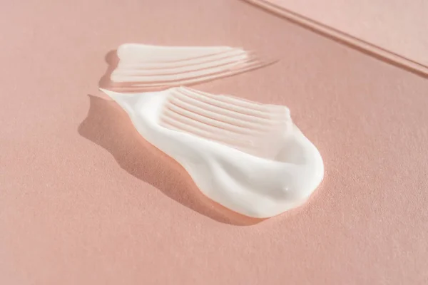 Pembe arka planda beyaz krem lekesi. Kremin dokusu..