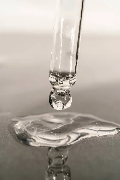 Serumun veya yağın gri arka planda pipeti olan dokusu.