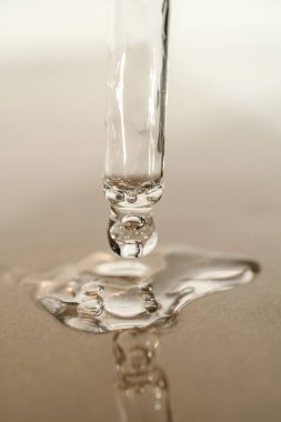 Serumun dokusu ya da bej arka plandaki pipetten dökülen yağ..