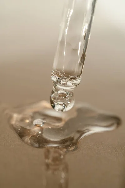 A textura de soro ou óleo com uma pipeta em um fundo bege. — Fotografia de Stock