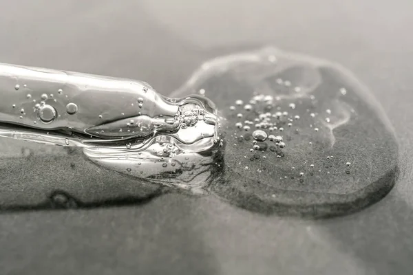 Konsistensen av serum eller olja med en pipett på en grå bakgrund. — Stockfoto