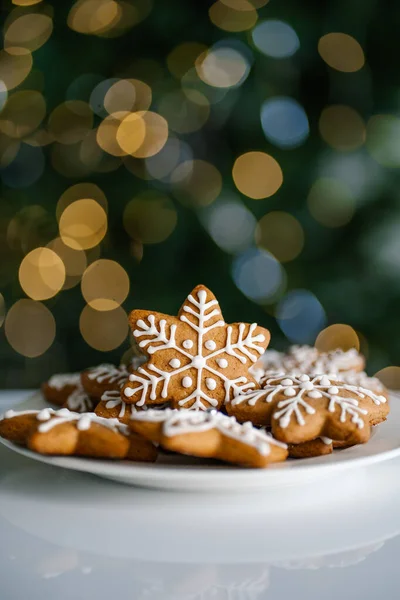 Imbirowe ciasteczka świąteczne na tle choinki ze światłami. — Zdjęcie stockowe