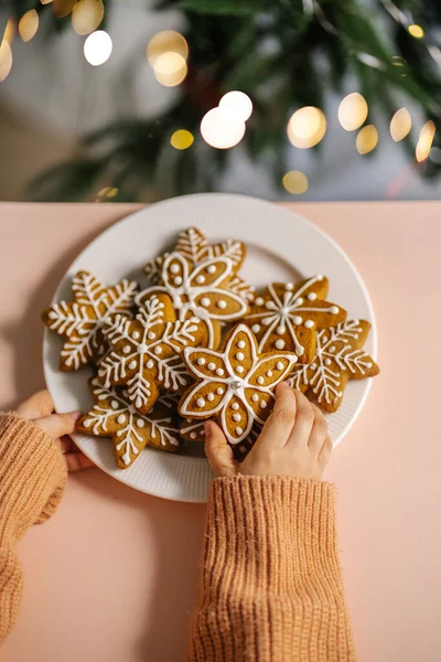 ジンジャークリスマスクッキー子供の手でクリスマスツリーの背景に. — ストック写真