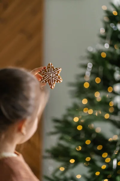 크리스마스 트리 뒤에서 손에 쥐고 있는 진저 크리스마스 쿠키. — 스톡 사진