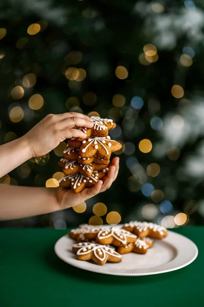 Galletas de Navidad de jengibre en manos de niños en el fondo del árbol de Navidad. — Foto de Stock