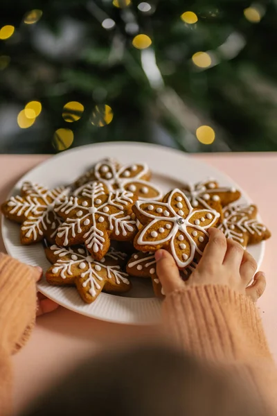 Galletas de Navidad de jengibre en manos de niños en el fondo del árbol de Navidad. — Foto de Stock