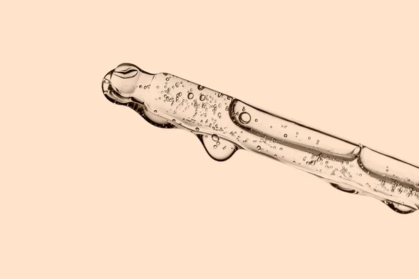 Bej arka planda kozmetik ürünleri olan şeffaf pipette. — Stok fotoğraf