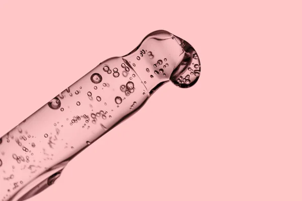 Transparent pipett med kosmetika på en rosa bakgrund. — Stockfoto