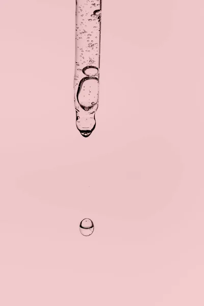 Przezroczysta pipeta z kosmetykami na różowym tle. — Zdjęcie stockowe
