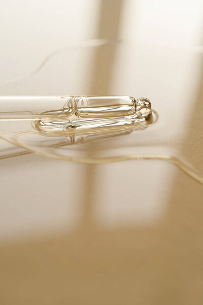 Pipette with oil or serum on a golden background.