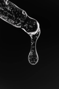 Siyah arka planda kozmetik ürünleri olan şeffaf pipet.