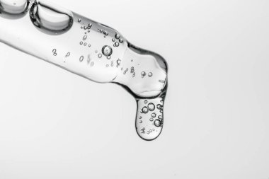 Beyaz izole bir zemin üzerinde kozmetik ürünleri olan şeffaf pipet.
