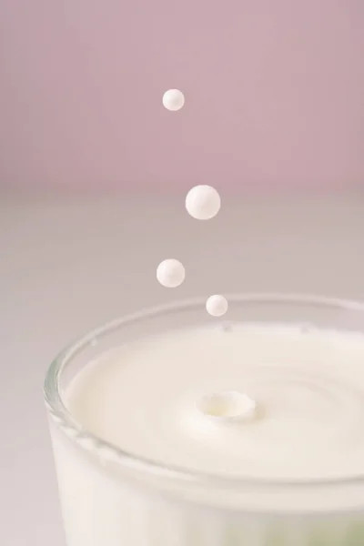 Il latte gocciola in un vetro trasparente sfaccettato. — Foto Stock