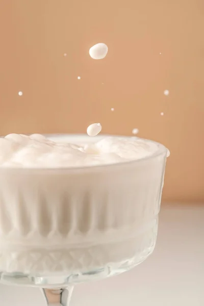 Mleko wlewa się do pięknej kryształowej szklanki i rozpryskuje wokół. — Zdjęcie stockowe
