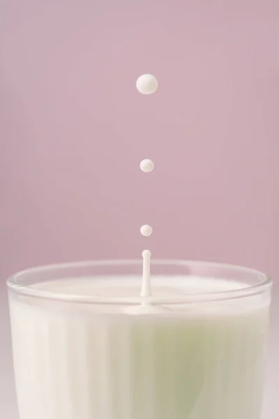 O leite goteja em um vidro facetado transparente. — Fotografia de Stock
