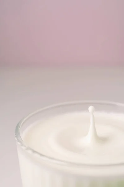 La leche gotea en un vidrio facetado transparente. — Foto de Stock