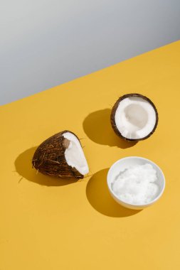 Bir kasede iki yarım hindistan cevizi ve hindistan cevizi yağı..