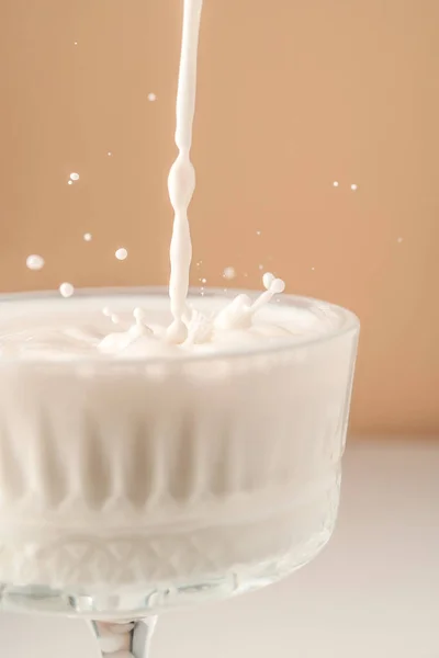 Mleko wlewa się do pięknej kryształowej szklanki i rozpryskuje wokół. — Zdjęcie stockowe