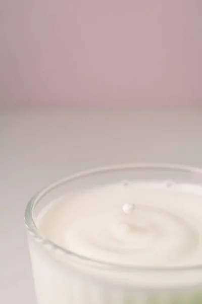 Il latte gocciola in un vetro trasparente sfaccettato. — Foto Stock