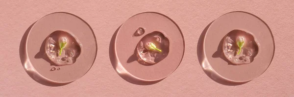 Pembe arka planda çiçek olan bir damla kozmetik jel..