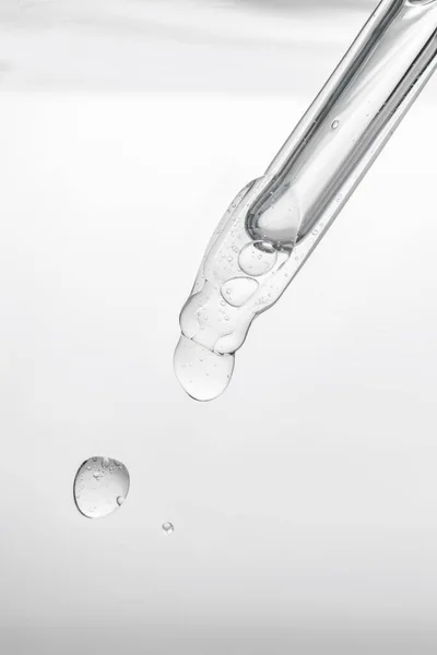 Pipeta con producto cosmético en agua con burbujas. — Foto de Stock