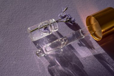 Mor arka planda bir şişe kozmetik jel ve lavanta.