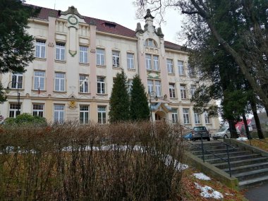 - Okul. Parktaki ilkokulun mimari binasının önü ağaçların ve çitlerin arasında.. 