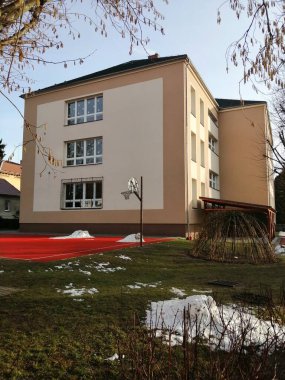 Okul bahçeli. Kışın çocuk parkı ve okul bahçesi olan, küp kare okul binası.. 