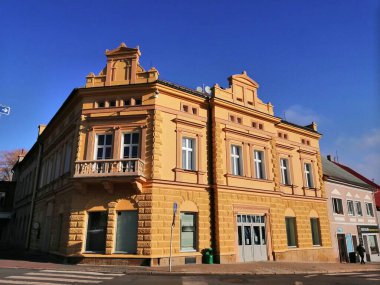 Madalyalı mimari. Köşedeki tarihi bina, balkonlu. Meydanın köşesinde bir dükkan.. 