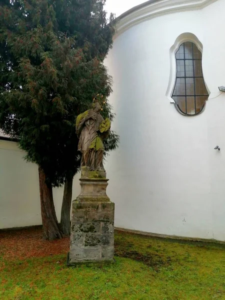 Άγαλμα Ένα Πέτρινο Άγαλμα Φωτοστέφανο Μπροστά Από Μια Λευκή Εκκλησία — Φωτογραφία Αρχείου