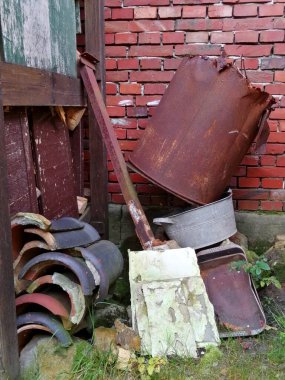 Tuğla evin arkasında bir yığın, eski demir, çatı kiremitleri, moloz. 
