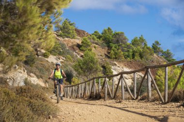 İtalya Toskana Takımadası 'ndaki Elba Adası' nda Akdeniz kıyısında elektrikli dağ bisikletine binen hoş bir kadın.