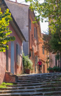 Elba, Toskana, Toskana, Tuscany, İtalya 'daki Poggio adasındaki güzel köyü keşfeden elektrikli dağ bisikleti süren güzel aktif bir kadın.