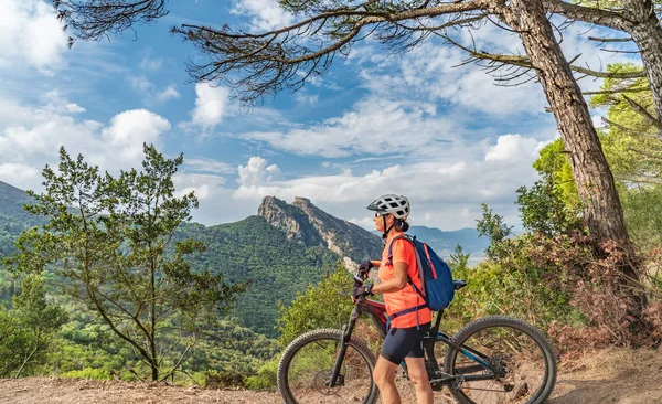 Elba Adası 'ndaki Akdeniz' in yukarısındaki Toskana Takımadası, Toskana, İtalya 'daki dağlarda elektrikli dağ bisikleti süren hoş bir kadın.