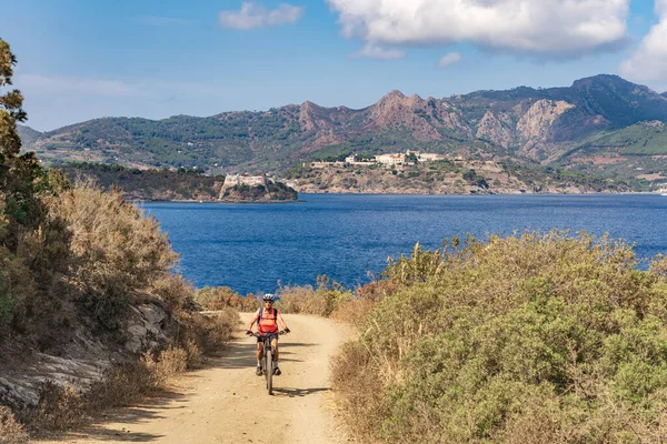 İtalya Toskana Takımadası 'ndaki Elba Adası' nda Akdeniz kıyısında elektrikli dağ bisikletine binen hoş bir kadın.